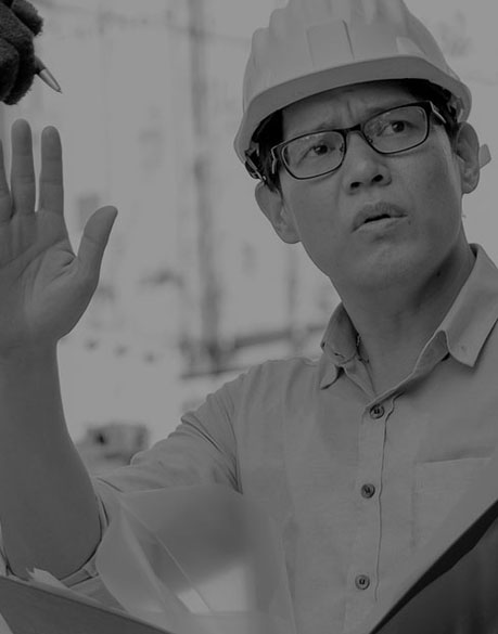 Chef de chantier avec casque et lunettes lève la main.