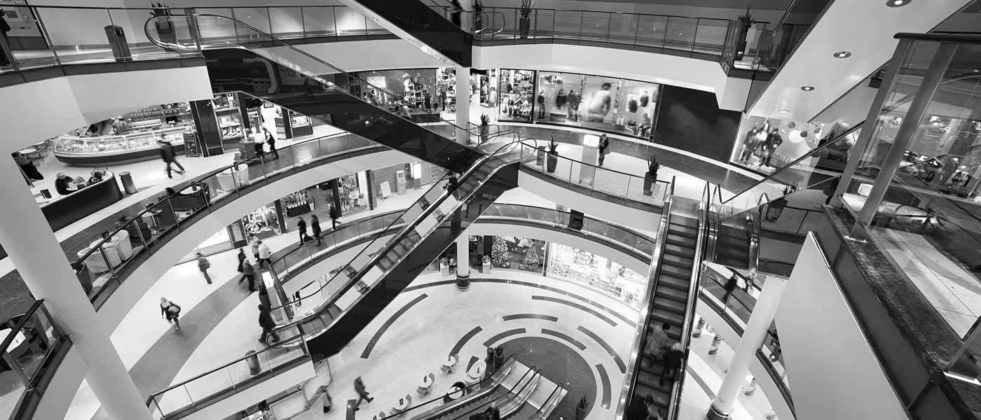 Vue de l'intérieur d'un Établissement Recevant du Public avec escalators, boutiques et visiteurs qui marchent